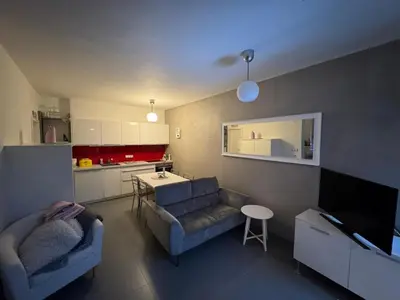 a living room with a couch and a kitchen at Prague Cozy Hideaway in Lysolaje