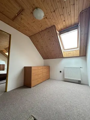 an attic room with a window and a wooden ceiling at Ubytování uprostřed Evropy in Kouřim