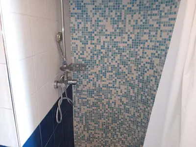 a bathroom with a shower with blue and white tiles at Cosy appartment close to main train station and city center in Prague