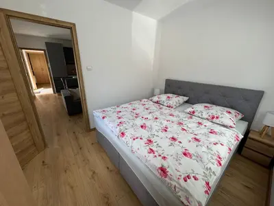 a bedroom with a bed with a floral comforter and a mirror at Domky Slapy pod golfem in Slapy