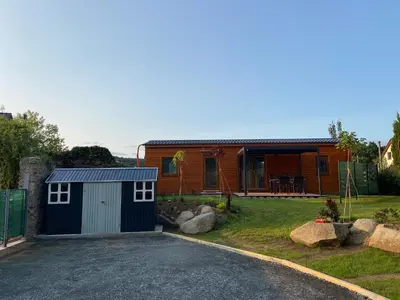 a black shed with a table and chairs on a deck at Domky Slapy pod golfem in Slapy
