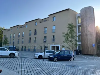 a parking lot with cars parked in front of a building at Prague Airport Family Lodging in Tuchoměřice