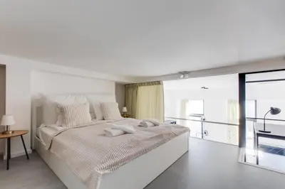 a white bedroom with a large bed and a balcony at Designer Loft Apartment Holešovice, Parking, Balcony in Prague