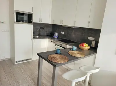 a kitchen with white cabinets and a table and chairs at Karlin Executive - Standing Desk, Monitor & Garage in Prague