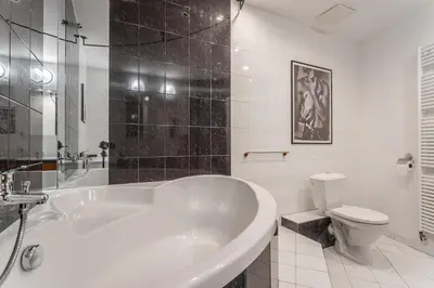 a white bathroom with a tub and a toilet at Parkview Penthouse in Prague