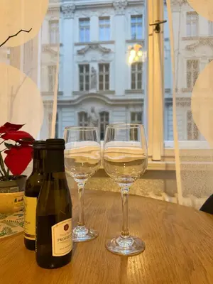 two glasses of white wine sitting on a wooden table at Cozy Prague Apartment in Prague