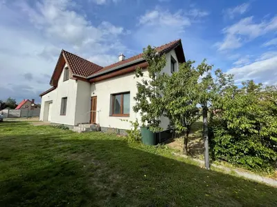 a white house with a tree in the yard at Domek Nad Drahou Mělník in Pšovka