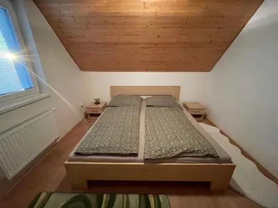 a bed in a small room with a wooden ceiling at Domek Nad Drahou Mělník in Pšovka