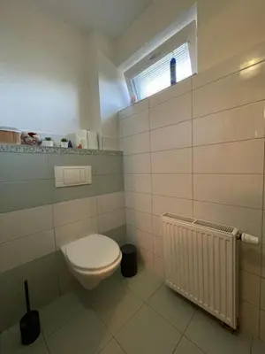 a white bathroom with a toilet and a window at Domek Nad Drahou Mělník in Pšovka