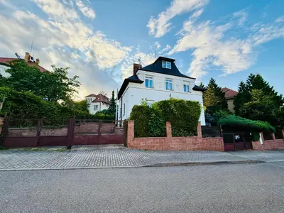 a white house with a black roof and a fence at Family Villa Hanspaulka in Prague