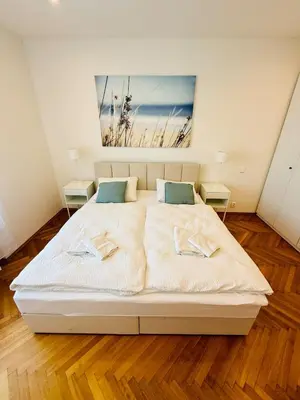 a bedroom with a large white bed with a painting on the wall at Family Villa Hanspaulka in Prague