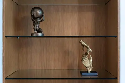 a bronze statue of a woman holding a shoe on a shelf at Golden Cat Suite in Prague