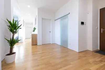an empty room with wooden floors and a plant at Airport Prague Luxury Apartment & Spa in Prague