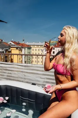 a woman in a bikini drinking a glass of wine in a hot tub at Royal Elephant Residence in Prague
