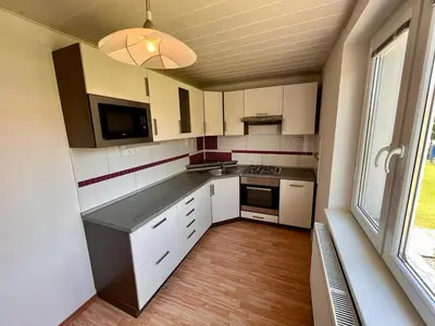 a kitchen with white cabinets and a large window at Apartmán u zámeckého parku in Všestudy
