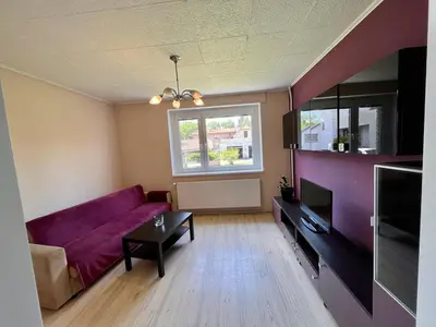 a living room with a purple couch and a window at Apartmán u zámeckého parku in Všestudy