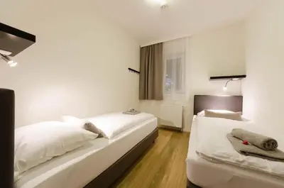 a white bedroom with two beds and a window at Pension Zličín in Prague