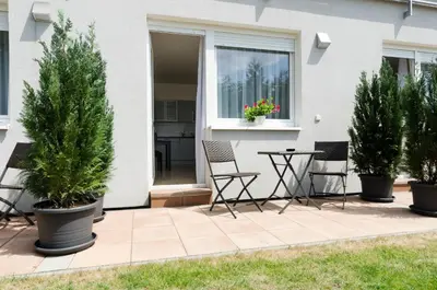 a patio with three potted trees and a table and chairs at Pension Zličín in Prague