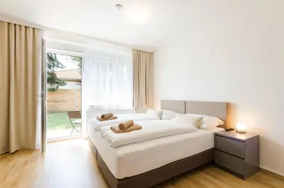 a white bedroom with a large bed and a window at Pension Zličín in Prague