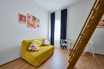 a living room with a yellow couch and a ladder at Sokolska apartment in Prague