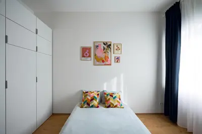 a bedroom with white walls and a bed with two pillows at Sokolska apartment in Prague