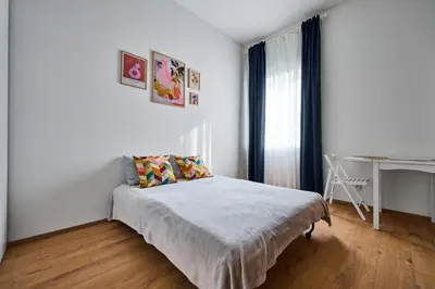 a white bedroom with a bed and a desk at Sokolska apartment in Prague