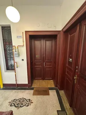 a hallway with wooden doors and a welcome sign on the floor at 1920s Charm apartment by Jerusalem Synagogue in Old Town Center in Prague