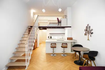 a kitchen and living room with a staircase and a table at LuxeLoftPrague in Prague