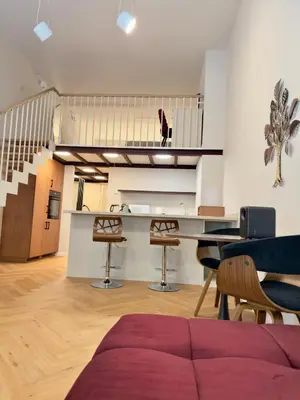a living room with a table and chairs and a staircase at LuxeLoftPrague in Prague