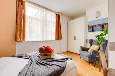 a bedroom with a bed and a chair and a window at Quaint Trendy Apartment in Prague