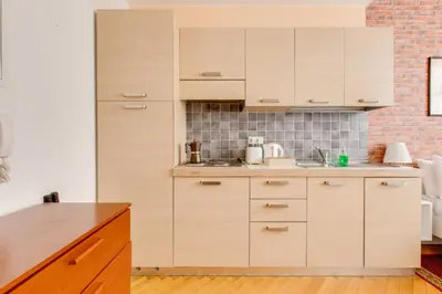 a kitchen with white cabinets and a brick wall at Quaint Trendy Apartment in Prague