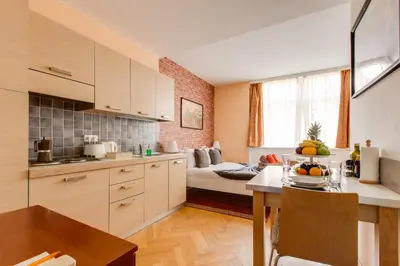 a kitchen with white cabinets and a living room at Quaint Trendy Apartment in Prague