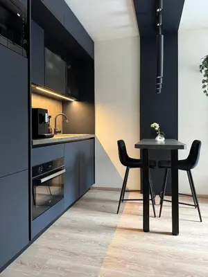 a kitchen with black cabinets and a table at Smarty Choice Living with Netflix - Kubanske namesti in Prague