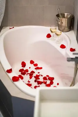 a bath tub filled with red roses and two glasses of wine at Bohemian Emperors Residence in Prague