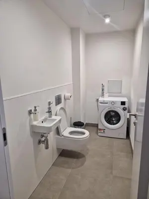 a bathroom with a toilet and a sink and a washing machine at Smichov Luxury Apartments Residence Madeleine in Prague