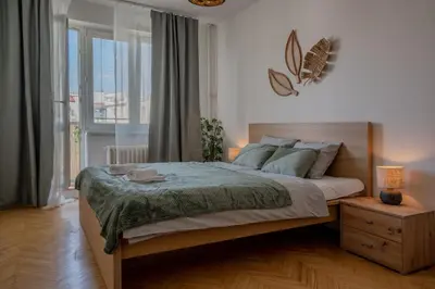 a bedroom with a large bed and a large window at Spacious residential apt with balcony by TV tower in Prague