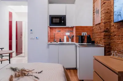 a kitchen with white cabinets and a brick wall at Apartment Dalimilova in Prague