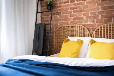a bed with two yellow pillows and a brick wall at Apartment Dalimilova in Prague
