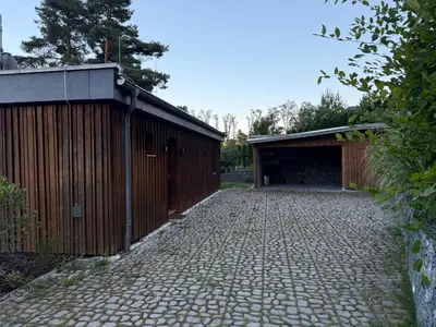 a garage with a brick driveway next to a building at Hrdlička Slapy Chalot in Buš
