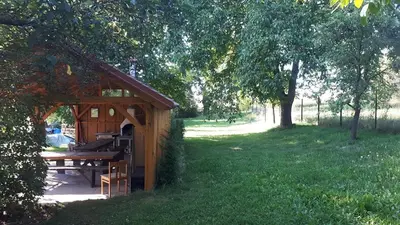 a wooden shed with a picnic table in a field at Chalupa u Kahounů in Popovice