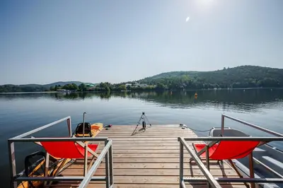 a dock with two chairs and a boat on the water at Slapy One&Only in Buš