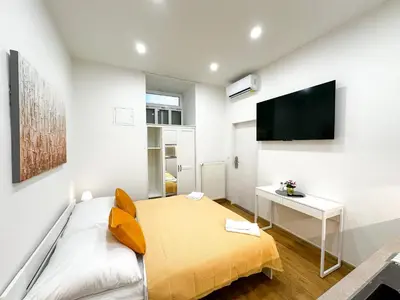 a bedroom with a bed and a desk and a tv at Krakovka Suites in Prague