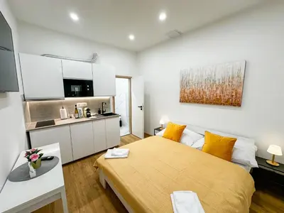 a bedroom with a large yellow bed and a kitchen at Krakovka Suites in Prague