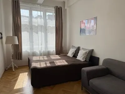 a bedroom with a bed and a couch and a window at CUBE Apt in Prague center in Prague
