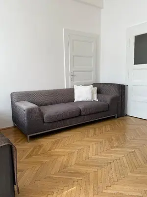 a gray couch in a living room with a wooden floor at CUBE Apt in Prague center in Prague
