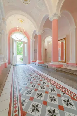 an ornate hallway with a tiled floor and columns at De Luxe Suite with balcony in Angelo Residence by Rentez in Prague