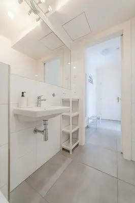 a white bathroom with a sink and a mirror at De Luxe Suite with balcony in Angelo Residence by Rentez in Prague