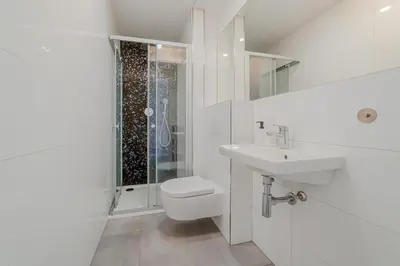 a white bathroom with a toilet and a sink at De Luxe Suite with balcony in Angelo Residence by Rentez in Prague