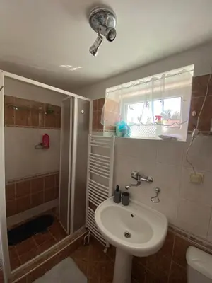 a bathroom with a sink and a shower with a window at Chalupa u Marušky