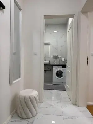 a white bathroom with a washing machine and a stool at Luxury Modern Apartment with View in Prague